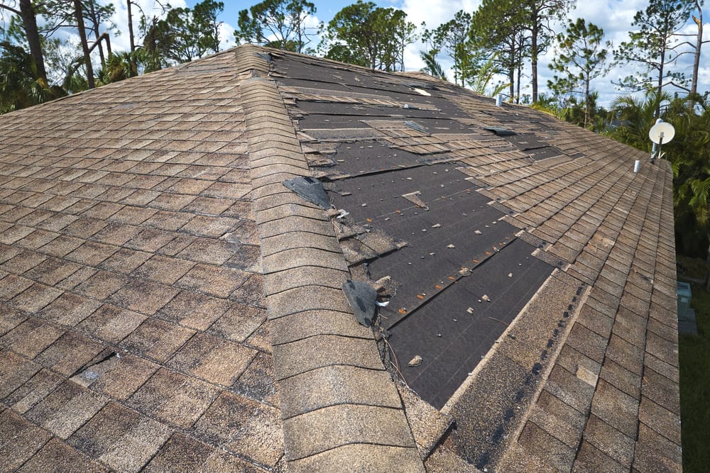 Damaged house roof with missing shingles