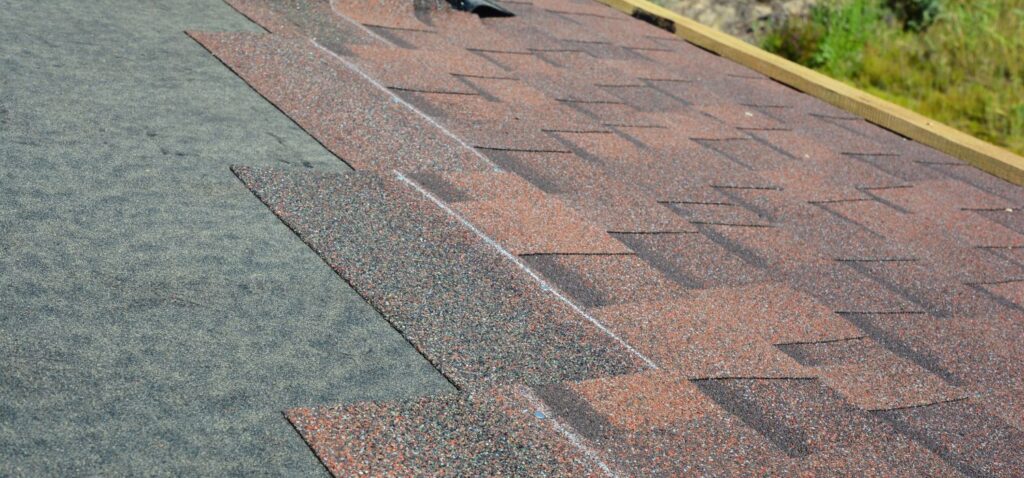 Close up of architectural asphalt shingles being installed on a residential roof during a roof replacement project.