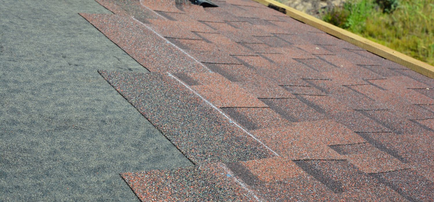 Close up of architectural asphalt shingles being installed on a residential roof during a roof replacement project.